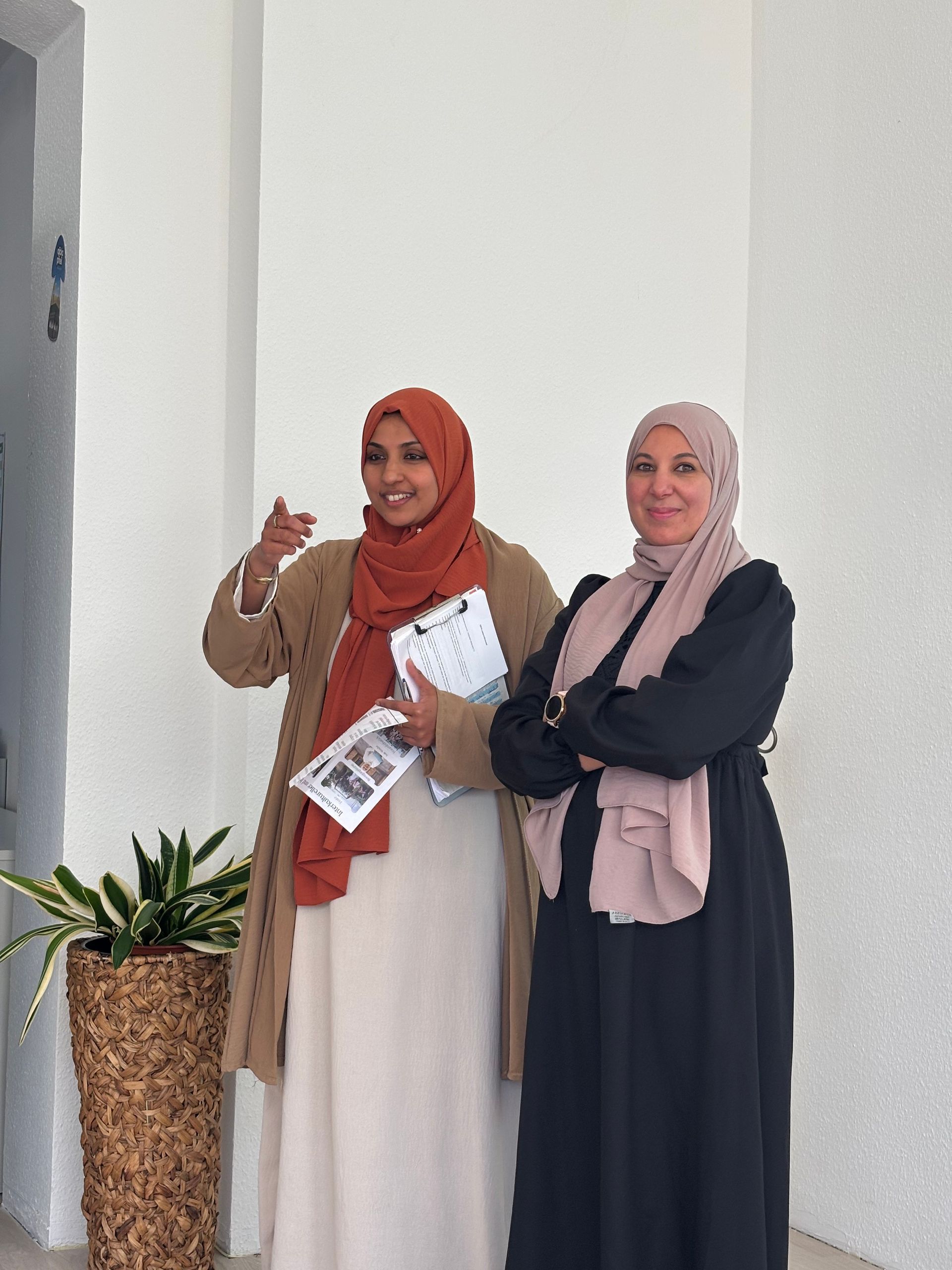 Zwei Frauen mit Kopftuch lächeln freundlich und sprechen zum (nicht sichtbaren) Publikum beim Auftakt von Her Diversity