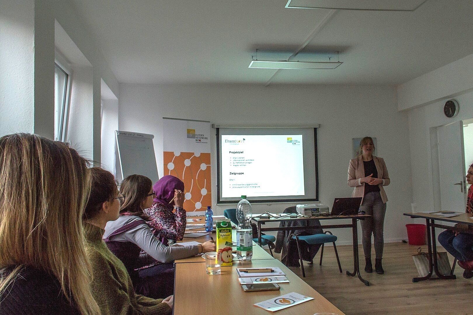 Infoveranstaltung des Eltern-Navis mit Leinwand und Präsentation, Frauen, die der Referentin gespannt zuhören