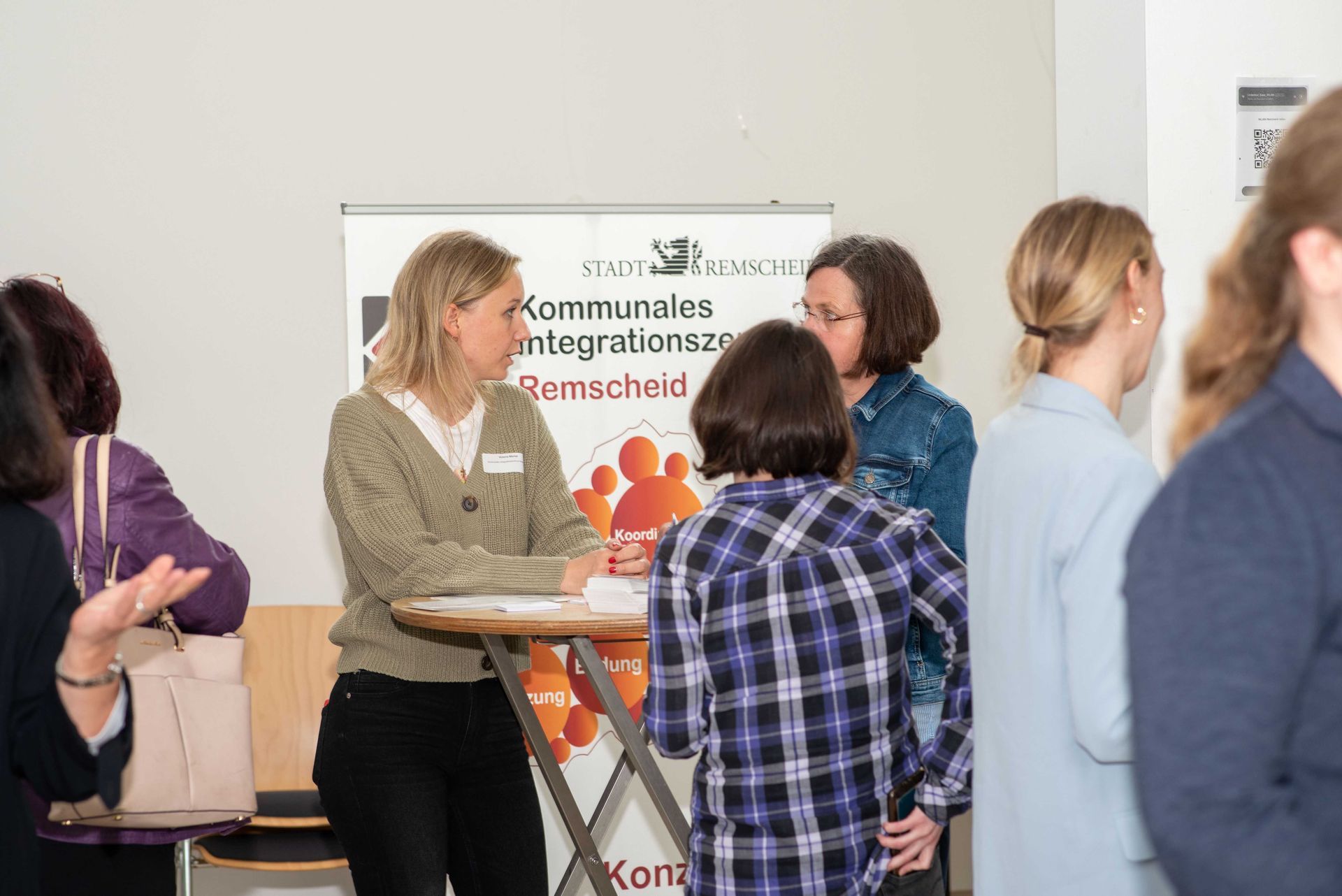 Teilnehmerinnen bei der Zukunftskonferenz im Gespräch. Im Hintergrund Aufsteller des Kommunalen Integrationszentrum Remscheid