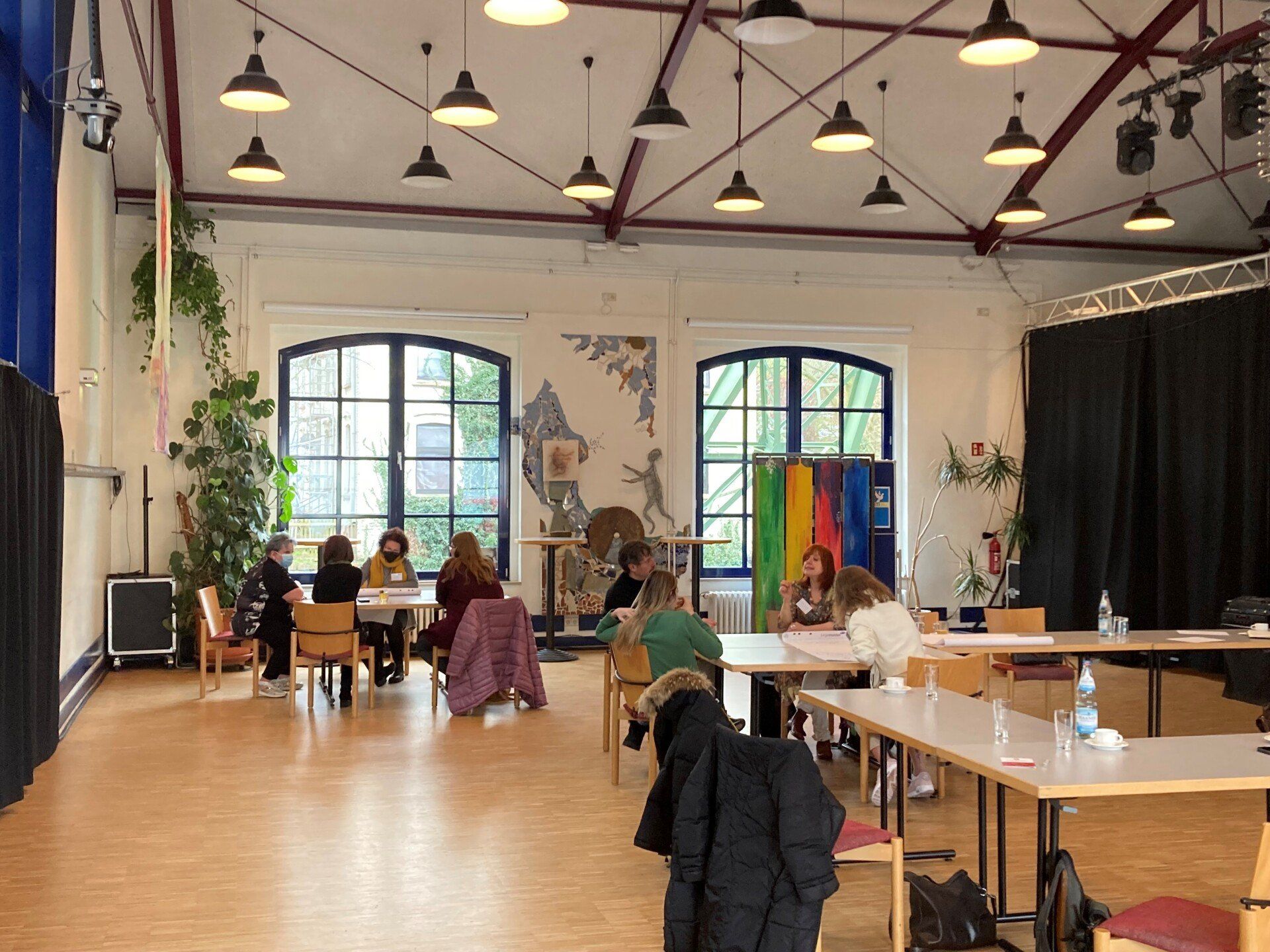 In einem Saal sitzen Eltern an zwei Gruppentischen. Sie kommen für das Projekt Kultur Inklusiv