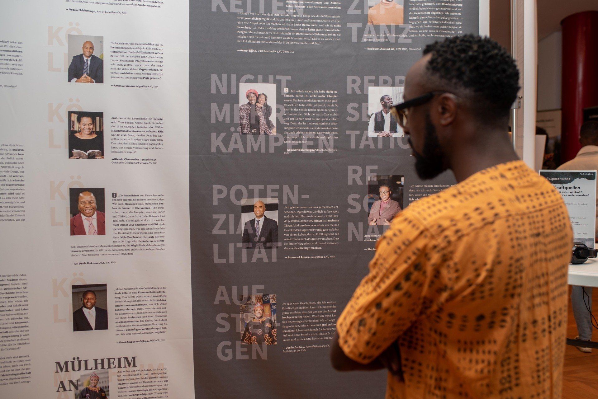 Ein Schwarzer Mann vor einer Informationswand mit verschiedenen Zitaten in der Ausstellung Meeting Diaspora.