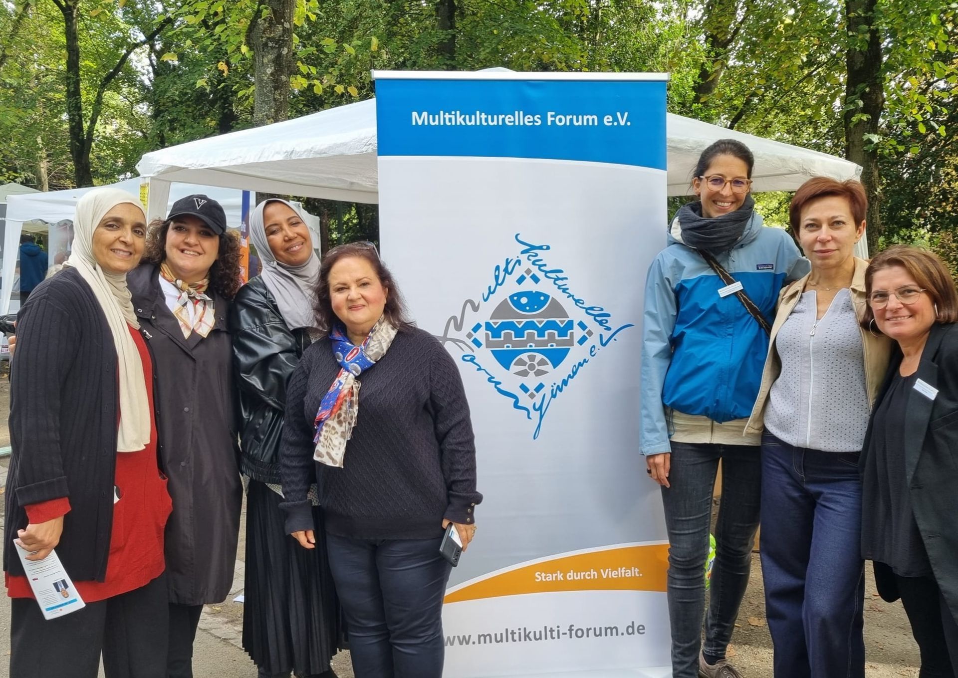 Es sind vereinsaktive Frauen neben dem Banner des Multikulturellen Forums zu sehen.