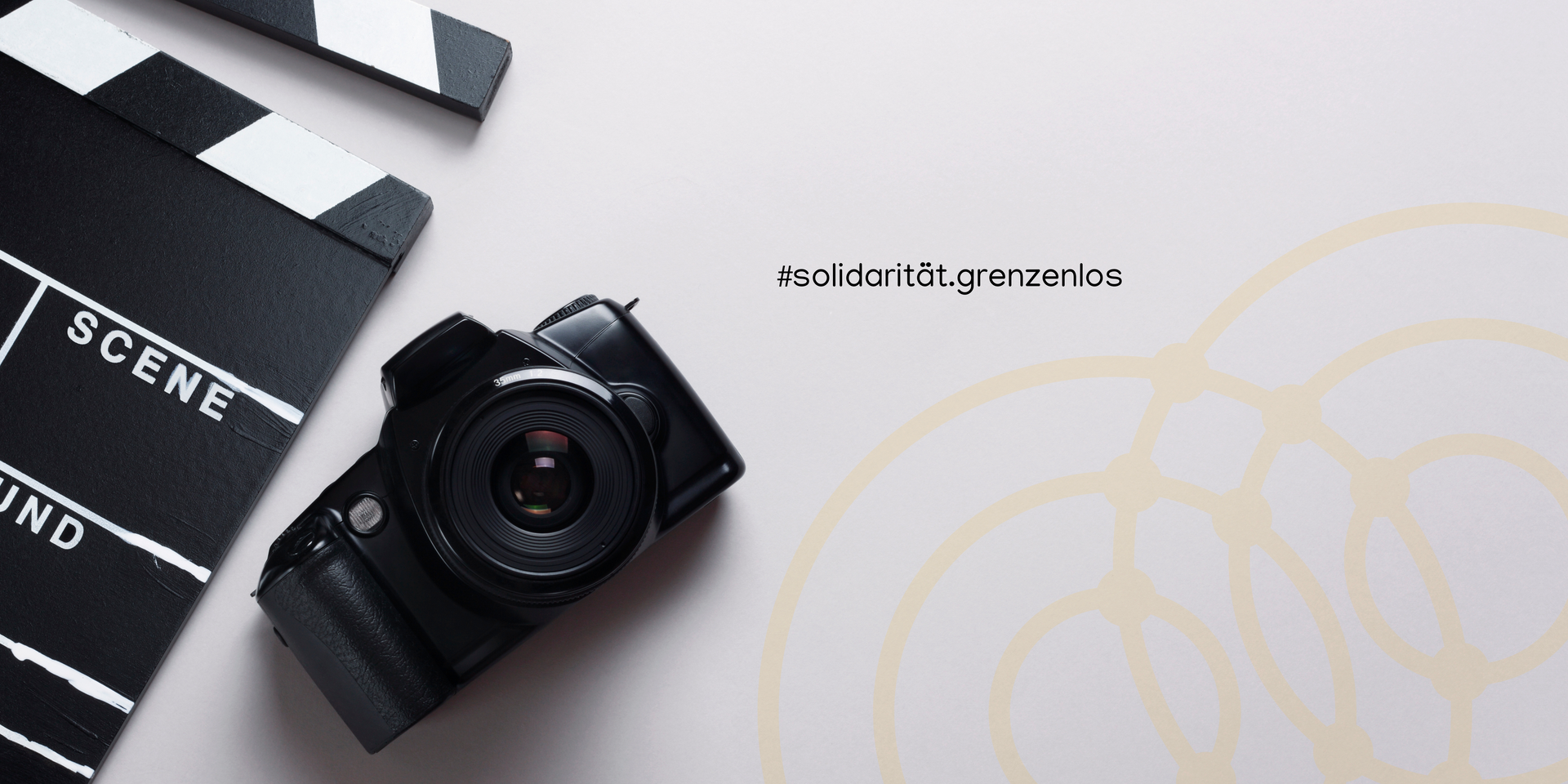 Kamera auf einer weißen Bildfläche, gelbe Logokreise des Elternnetzwerk NRW, Schriftzug #solidarität.grenzenlos. Link führt zu Projektseite der Aktionswochen gegen Rassismus