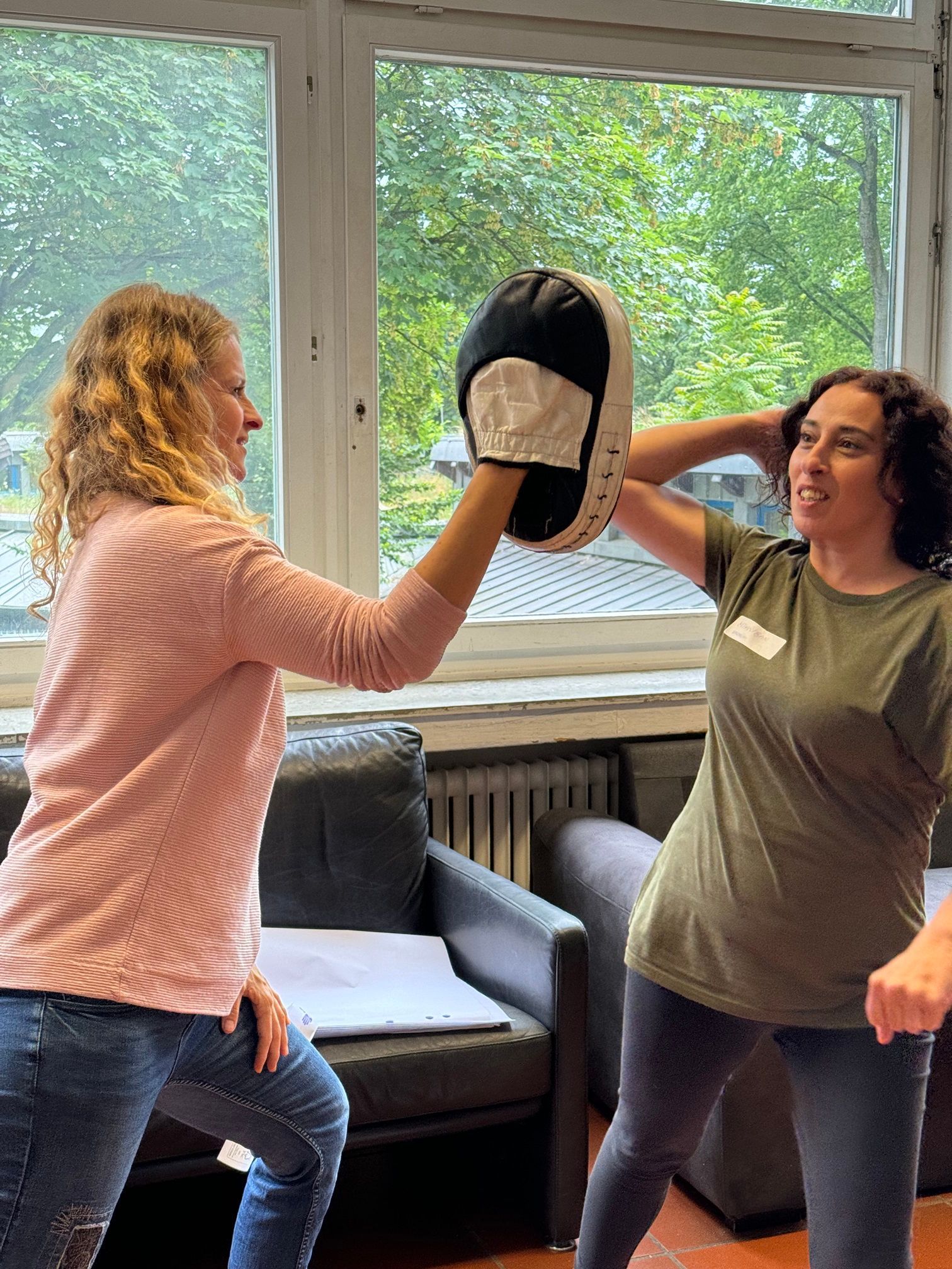Trainerin mit Frau, die zum Schlag auf Pratze ausholt. Im Projekt SelF - Selbstbehauptung für Frauen