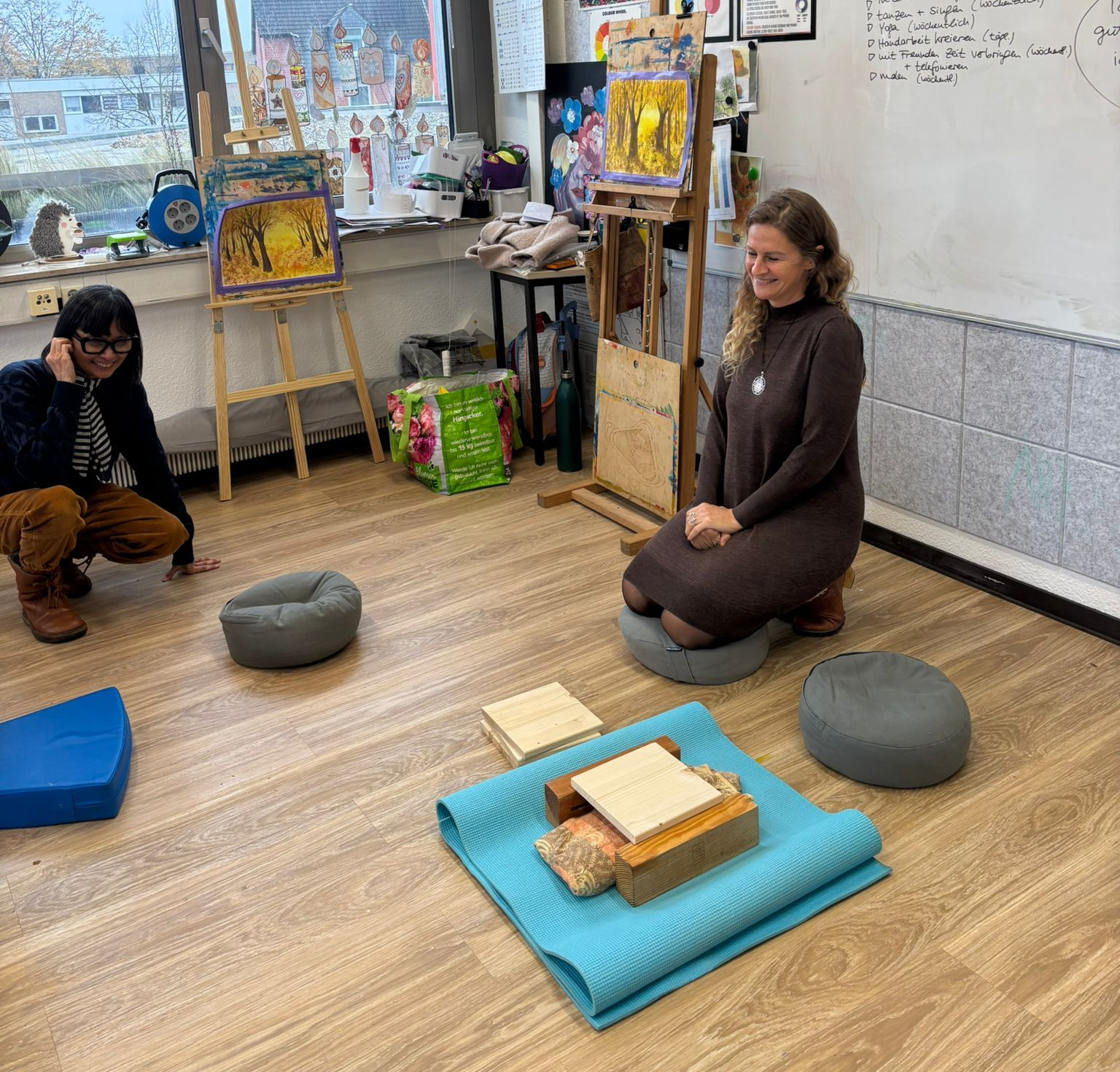 Auf dem Bild ist die Trainerin zu sehen sowie ein Brett zum Durchschlagen zur Selbststärkung.