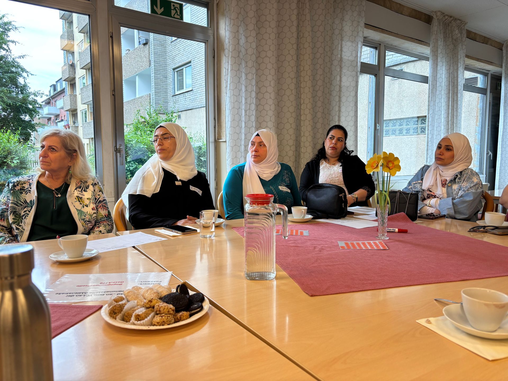 Teilnehmende Frauen sitzen an einem Tisch, hören aufmerksam zu und tauschen sich aus.