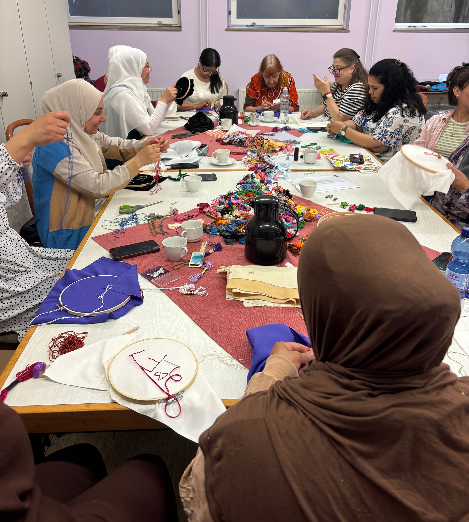Teilnehmerinnen beim Stick-Workshop, die gemeinsam mit bunten Garnen textile Werke gestalten.