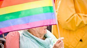 An elderly woman holding an lgbtq+ queer gay pride flag