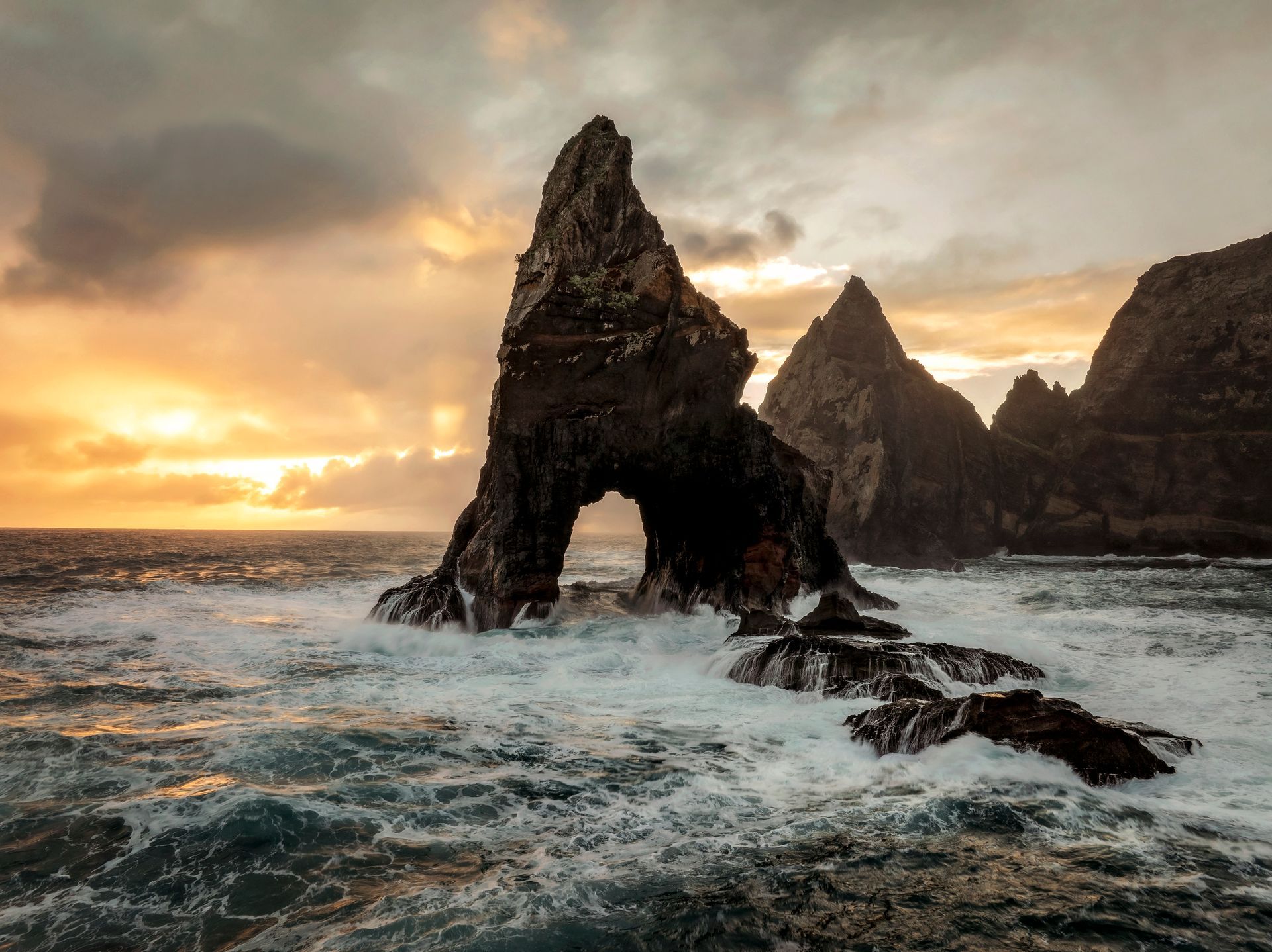 Waves crashing against a rock. Photo by Matthew Breiter Photography