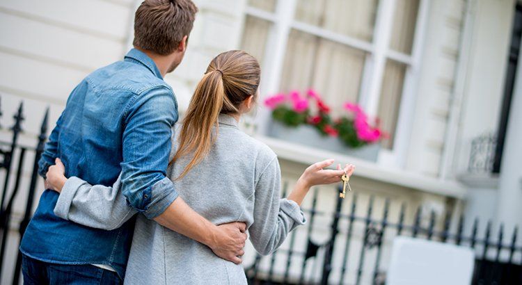 couple staning in front of home with keys