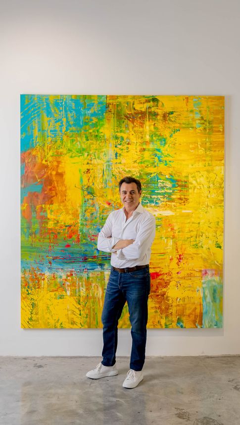 A man standing in front of a yellow painting