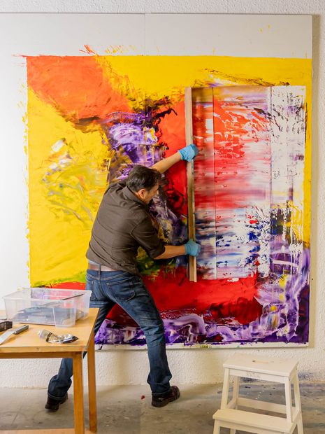 A man leaning on a wall standing in front of a painting