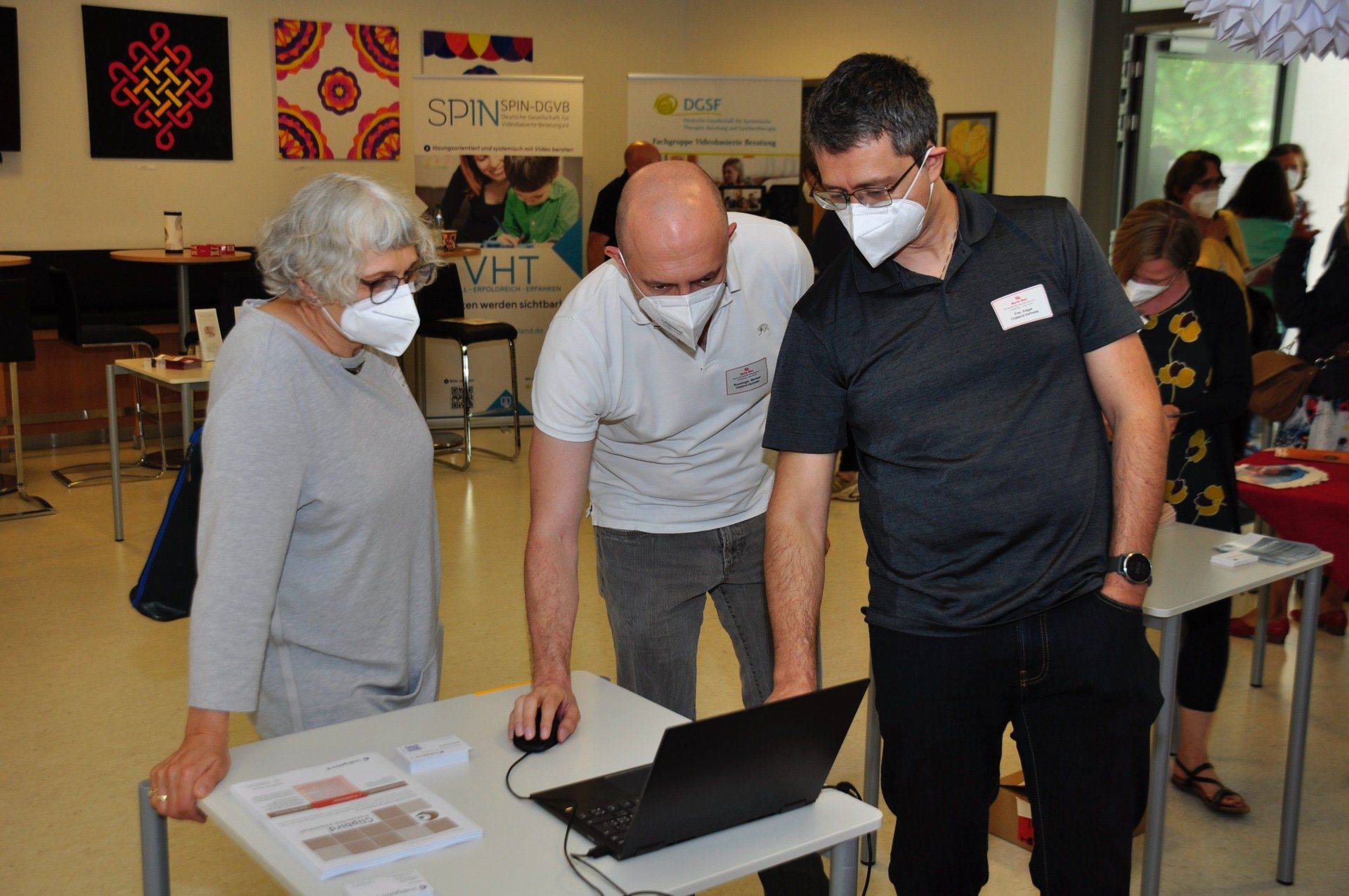 Frau Dr. Grevenkamp mit Clipbird-Vertretern am Marte Meo Fachtag in Bamberg Frau Dr. Grevenkamp steht an einem Tisch mit zwei Clipbird-Vertretern