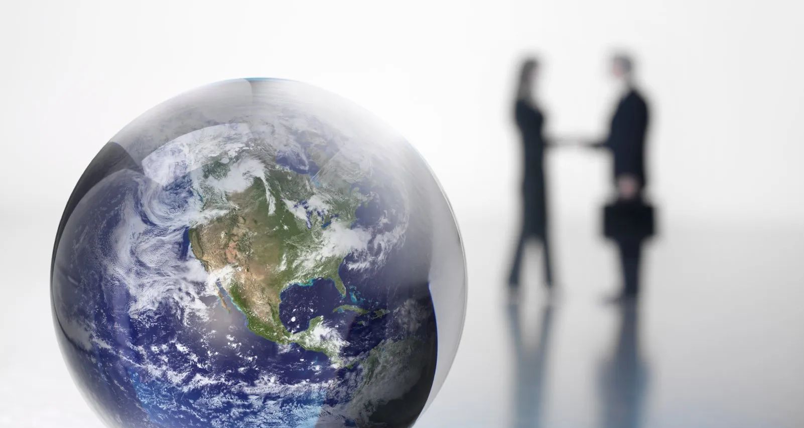 Eine Darstellung der Erde mit Fokus auf den amerikanischen Kontinent im Vordergrund. Im Hintergrund sind schemenhaft zwei Geschäftsleute zu sehen, die sich die Hand geben, was Zusammenarbeit und globale Partnerschaft symbolisiert. Die Szene verbindet das Thema Umweltschutz mit wirtschaftlicher Kooperation.
A depiction of the earth focussing on the American continent in the foreground. In the background, two business people can be seen shaking hands, symbolising cooperation and global partnership. The scene combines the theme of environmental protection with economic co-operation.