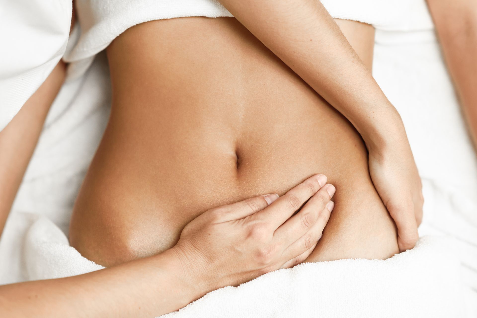 weibliche Hände berühren den Bauch einer Frau bei einer Frauenmassage