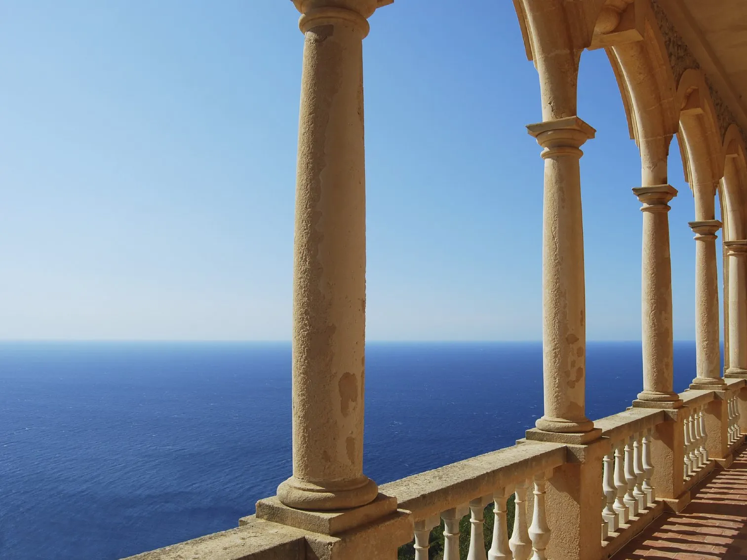 Blick auf weite blaue Meer durch geschwungene Bögen auf Säulen.