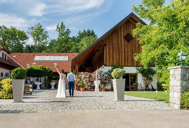 Brautpaar vor rustikalem Hochzeitsstadl im Freien.