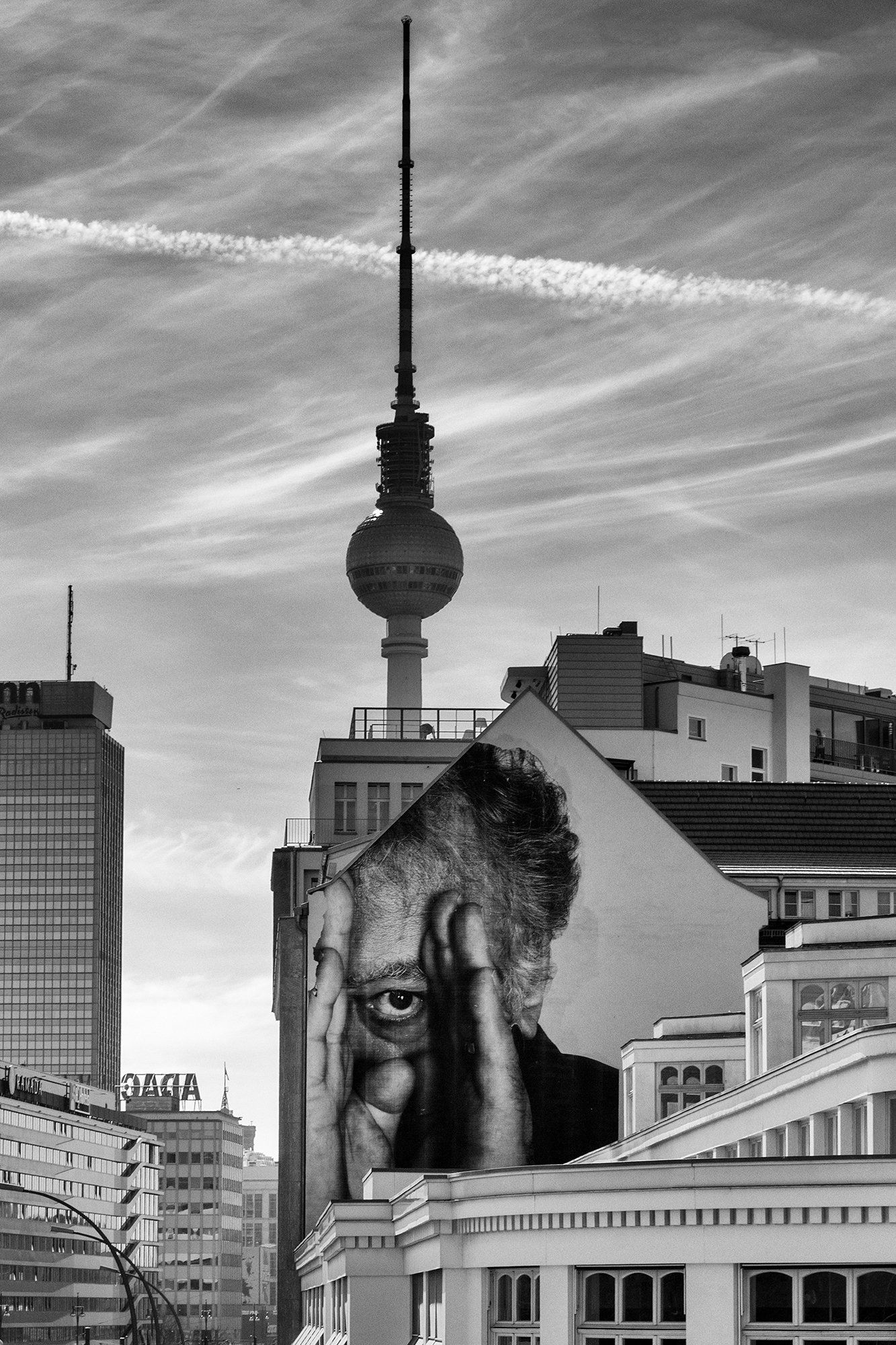 Berliner Fernsehturm hinter Hausfassade mit Wandbild. Schwarz weiß Stadtfotografie aus Berlin.