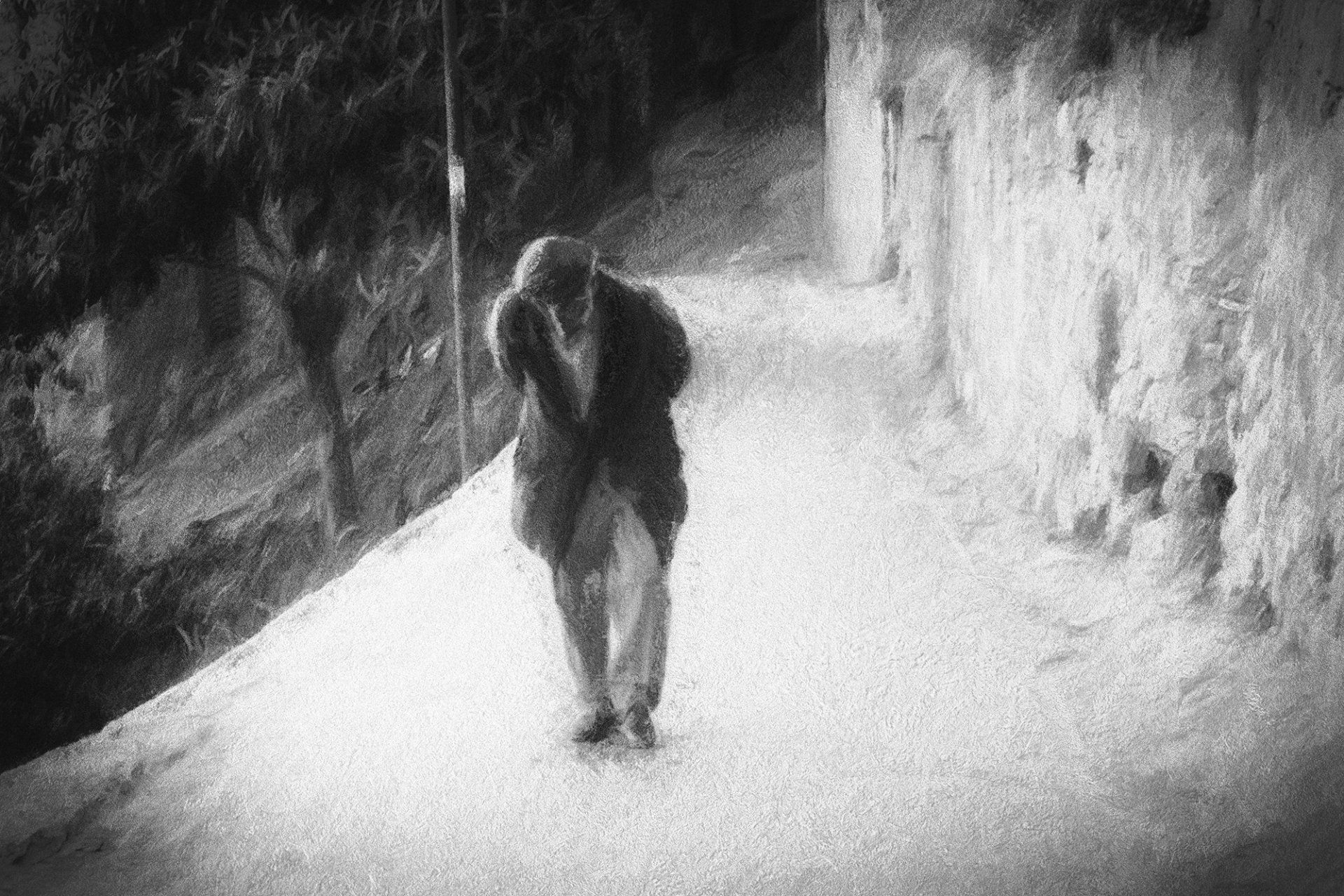 Ein älterer Mann geht langsam und gebeugt einen steilen Weg hinauf. Impressionistische Straßenfotografie aus Italien in schwarz weiß