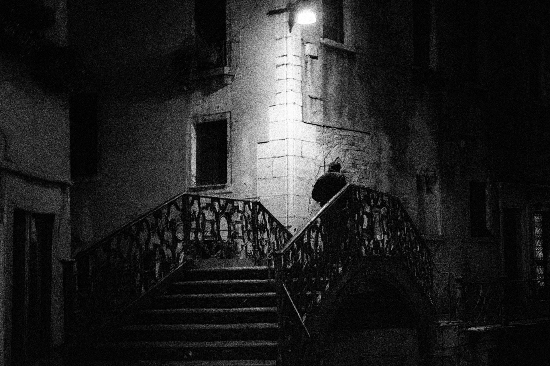 Street Photography Venedig - Eine Mann geht nachts allein über eine kleine Brücke in der Altstadt von Venedig