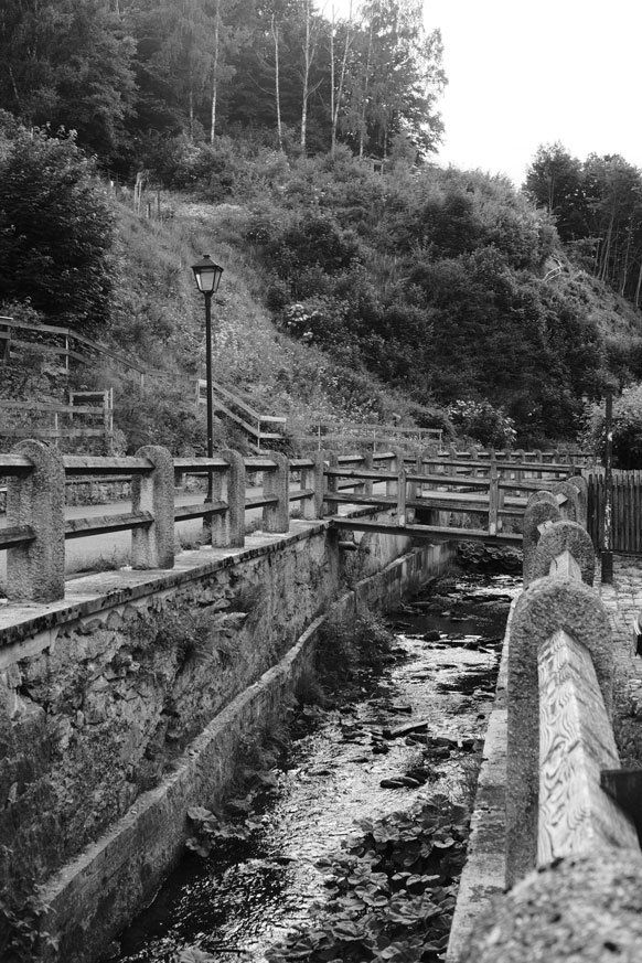 Schwarz weiß Fotografie eines Wassergrabens in der Altstadt von Stolberg im Harz