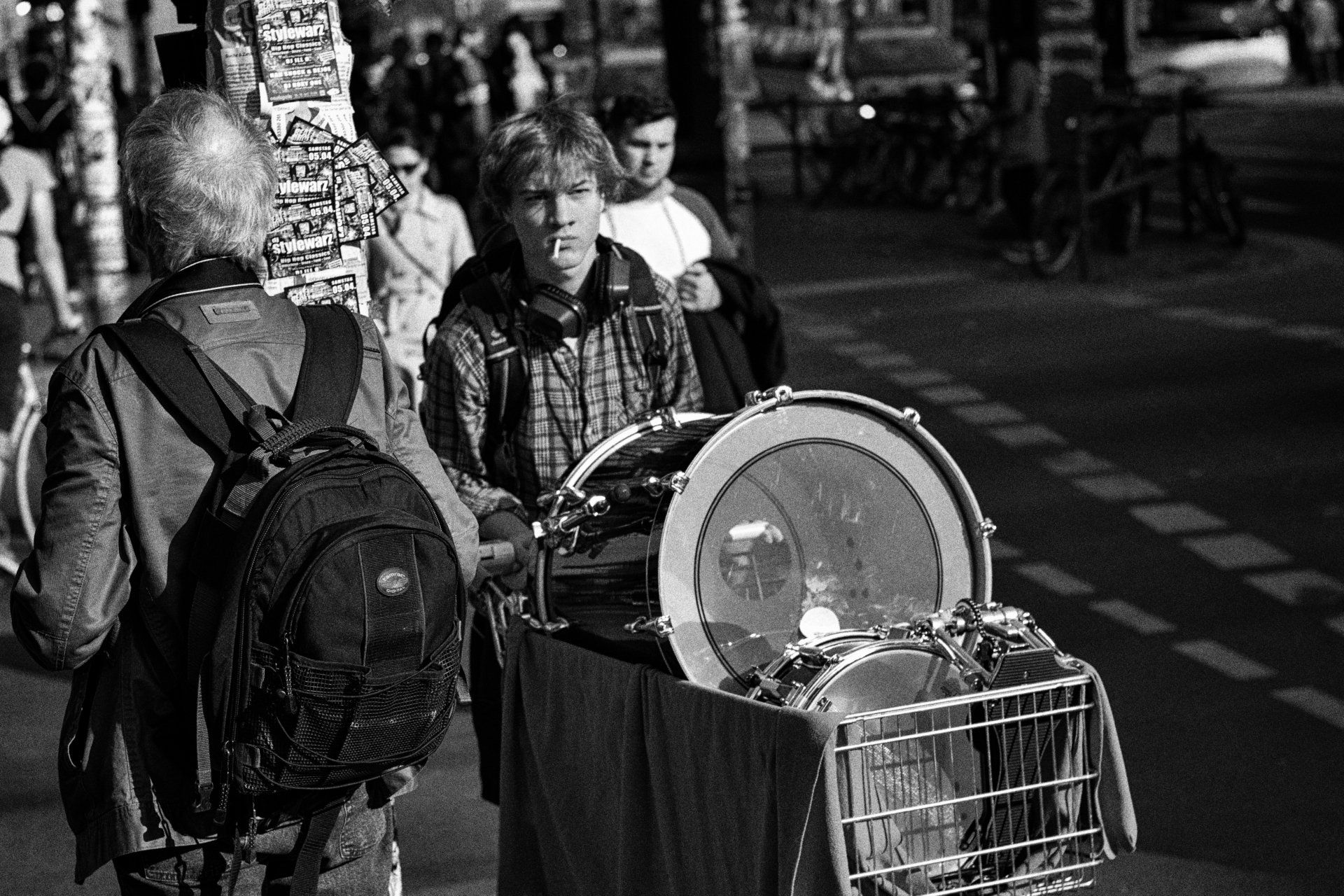 Ein junger Mann mit Igarette im Mund transportiert sein Schlagzeug in einem Einkaufswagen. Street photography aus Berlin in schwarz weiß.