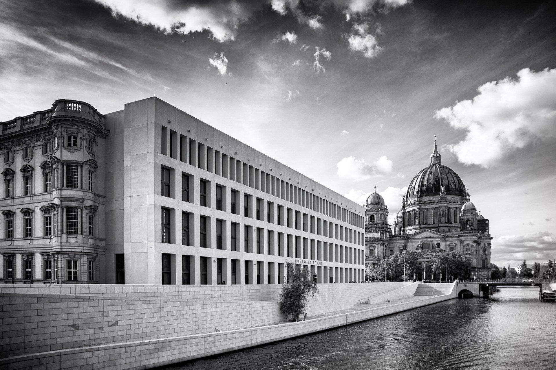 Am Ufer der Spree ist das neue Humboldt Forum gegenüber dem Berliner Dom fertiggestellt. Schwarz weiß Fotografie der beiden imposanten Bauwerke aus unterschiedlichen Epochen.