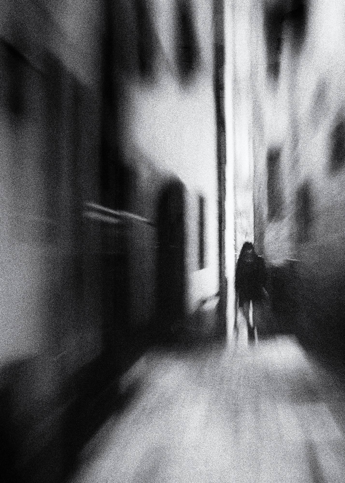 Eine junge Frau geht allein durch eine enge Gasse in der bezaubernden Altstadt von Barga in der Toskana. Abstrakte Straßenfotografie aus Italien in schwarz weiß