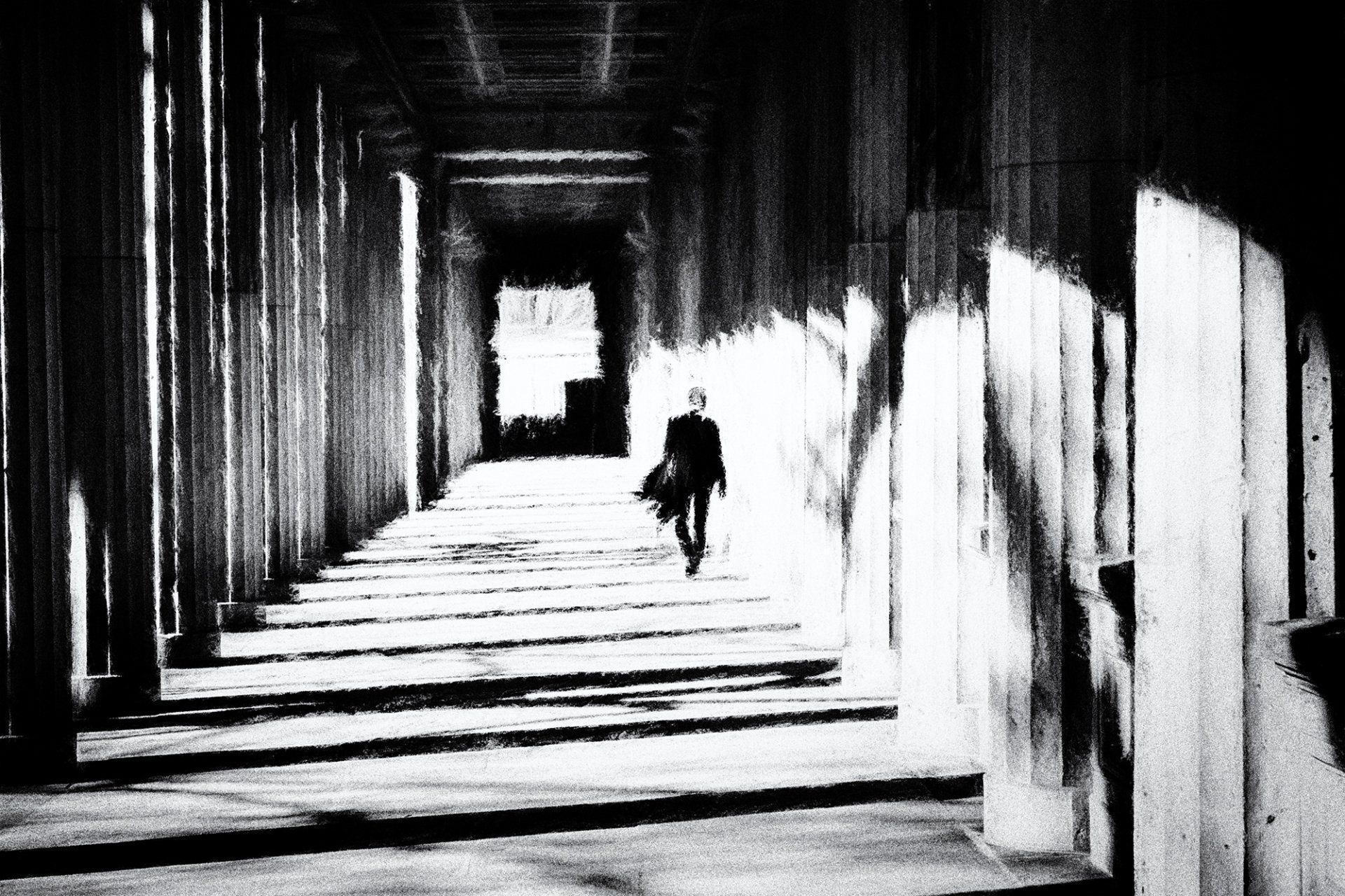 Ein Mann geht mit Mantel in der Hand entspannt durch die Arkaden des Lustgartens in Berlin. Impressionistische Straßenfotografie aus Berlin in schwarz weiß.