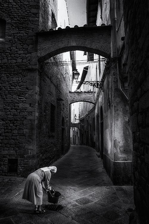 Schwarz weiß Straßenfotografie einer Nonne in einer engen Gasse von Pistoia Toskana. Limitierter Kunstdruck