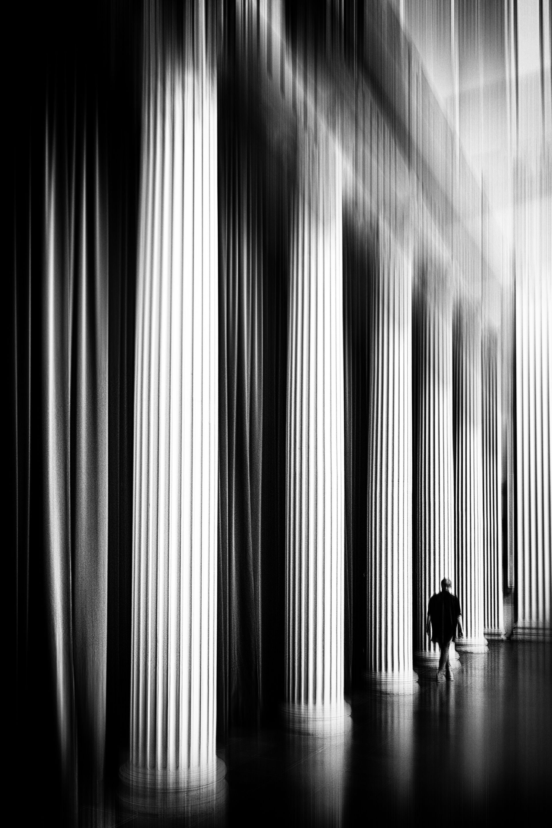 Schwarz weiß Fotografie Innenraum der Kirche St. Nikolai in Potsdam. Eine Frau geht allein entlang der Säulen.