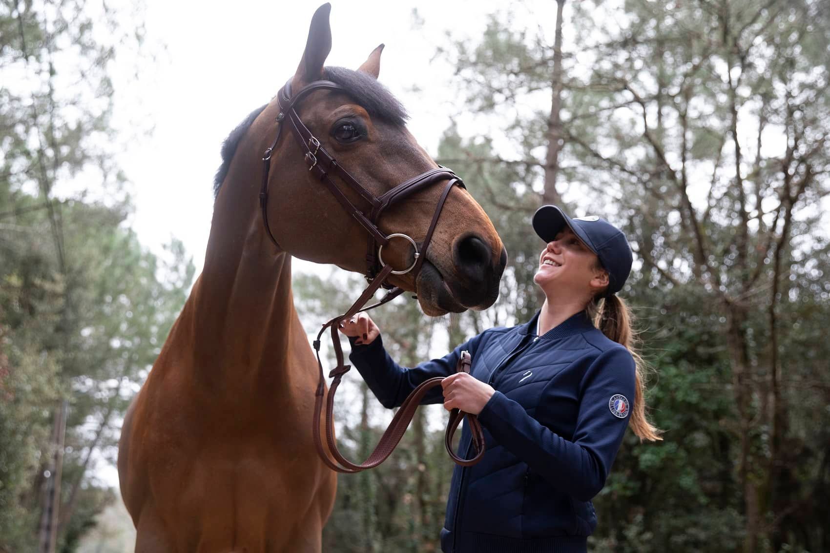 A woman in a white shirt rides a gray horse in a field at sunset.