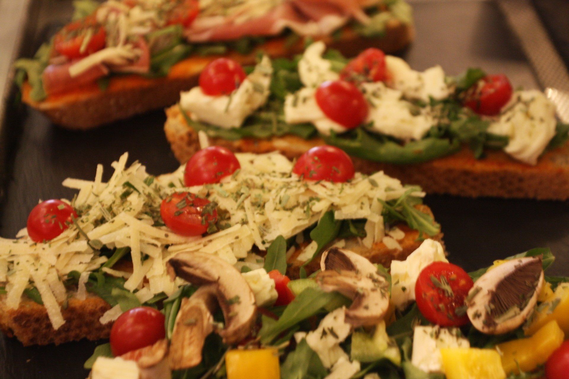 Bruschetta mit Tomatensalsa, Rucola und Cherrytomaten, wahlweise Schinken, Feta und Mozzarella