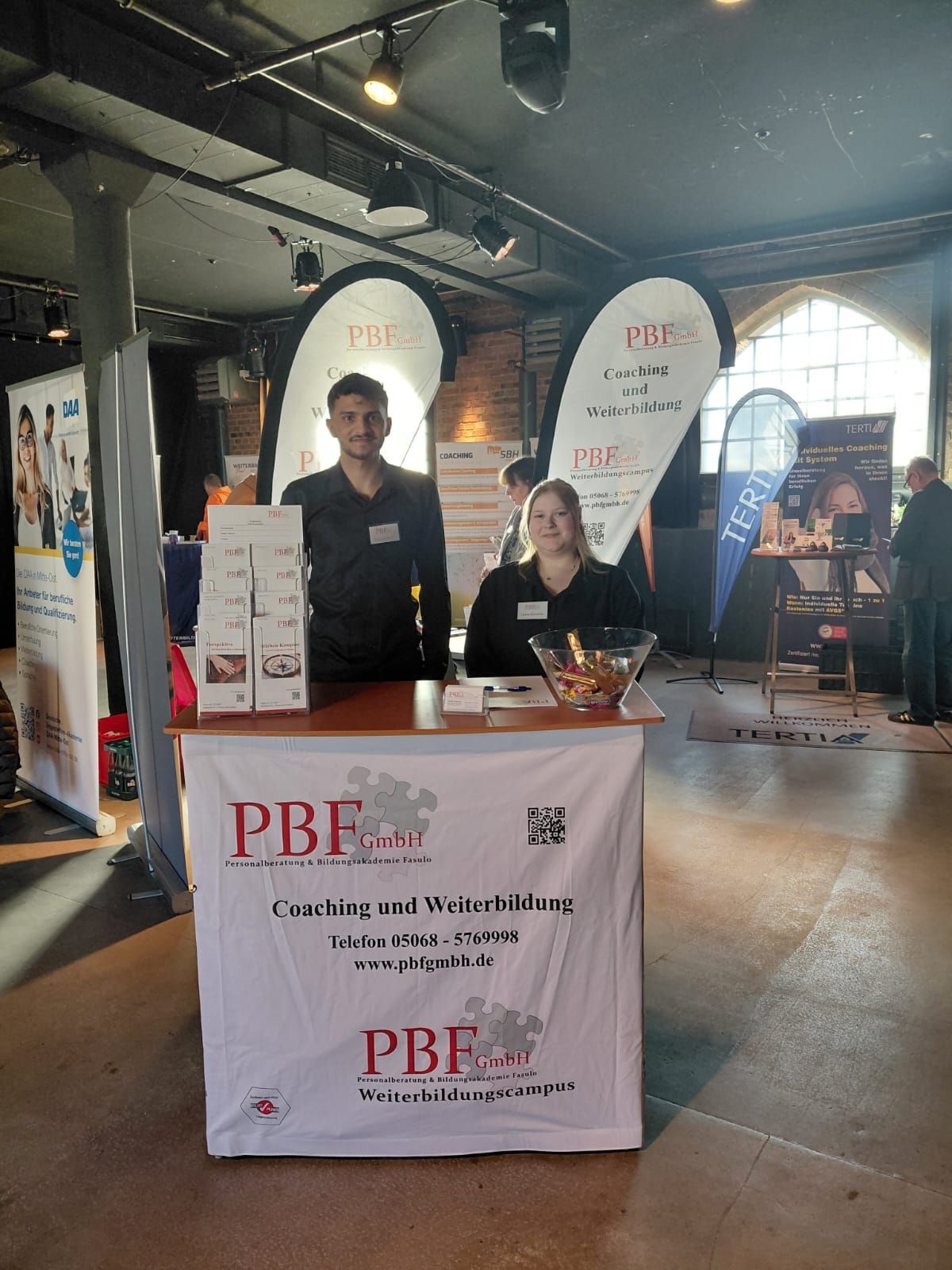 Mitarbeitende der PBF GmbH präsentieren das Unternehmen an einem Messestand auf einer Bildungsmesse