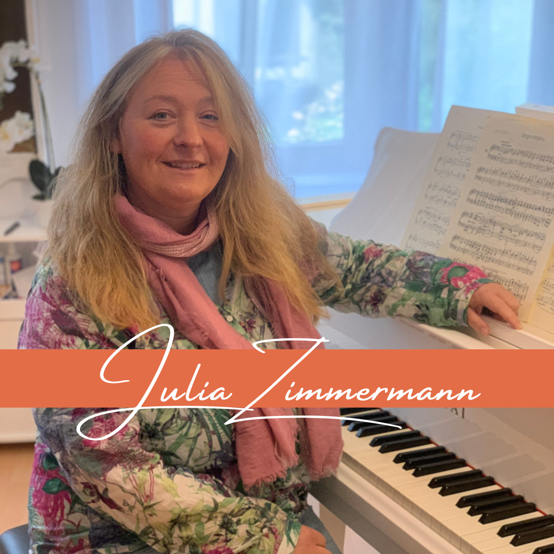 Blonde Frau am weißen Flügel mit Noten darauf, Frau schaut freundlich und hat bunte kleidung an mit einem rosa Schall