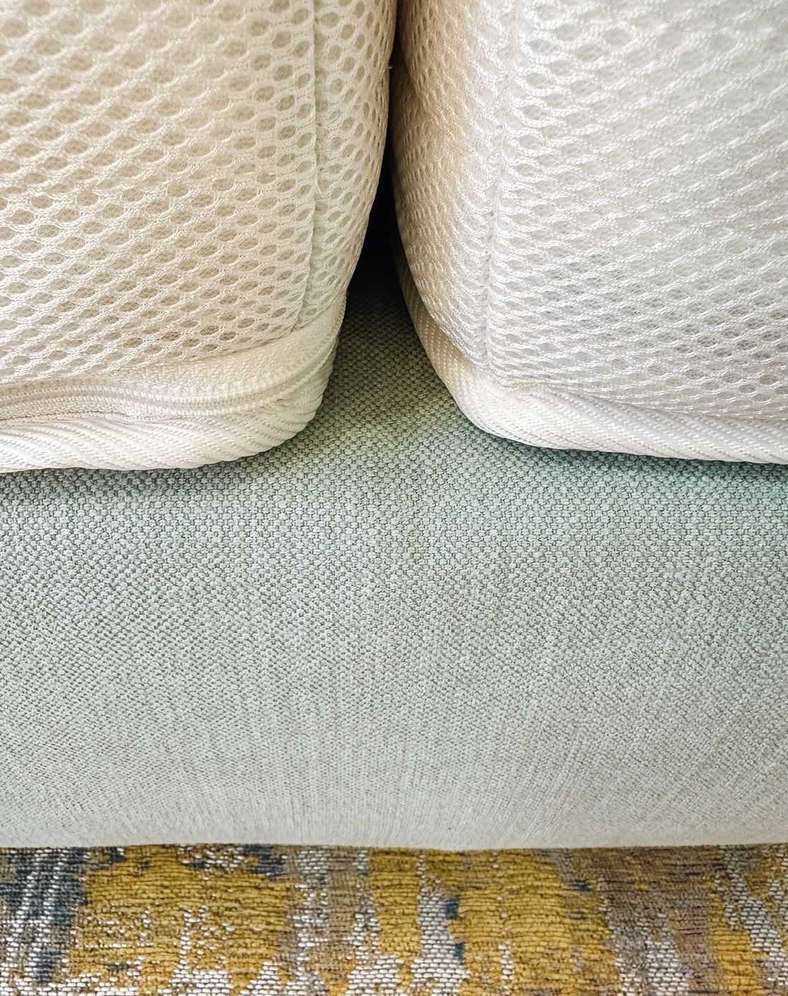 Detail eines Boxspringbettes, oben zwei Matratzen, unten derBettrahmen, auf dem Boden ein bunter Teppich