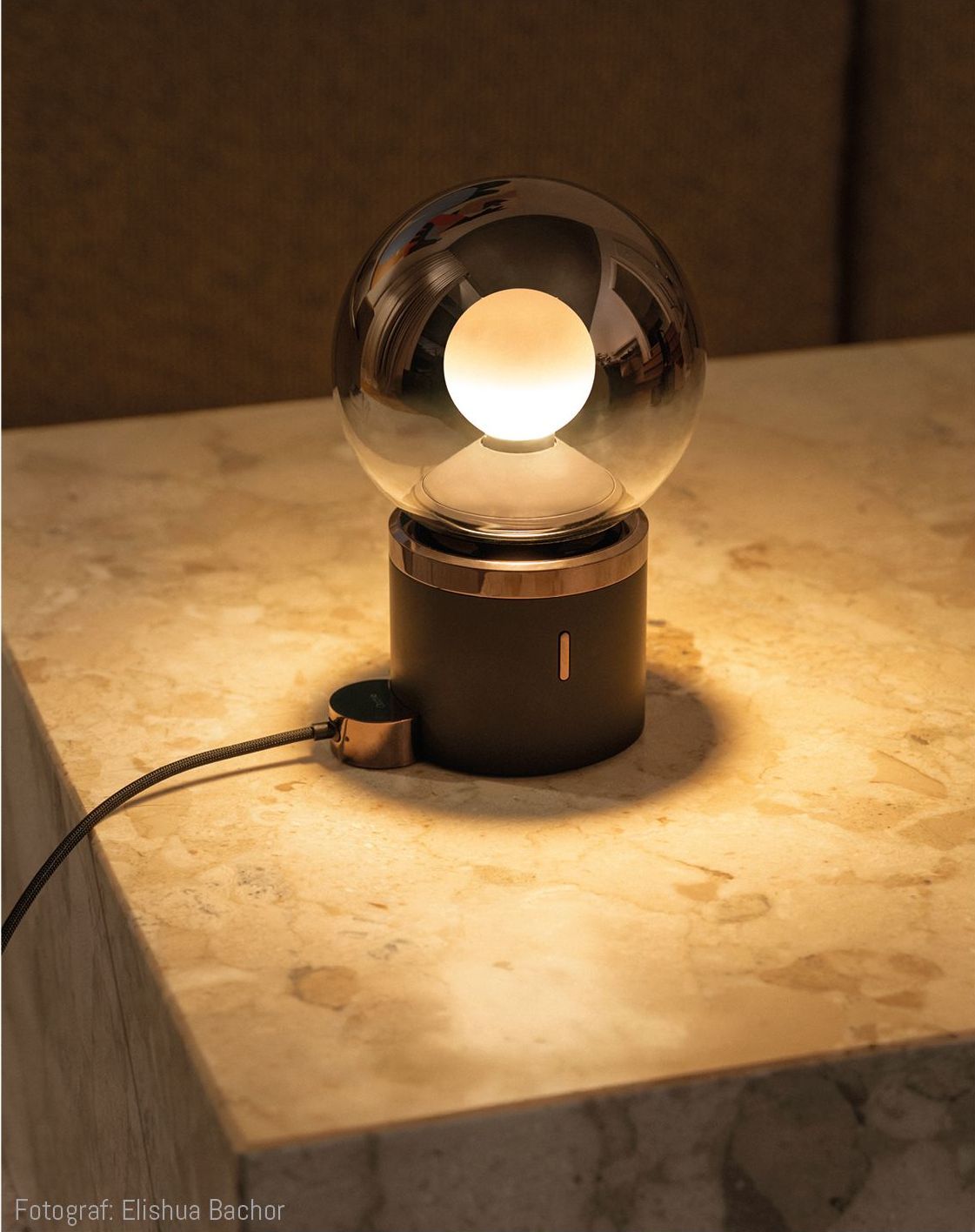 Tischleuchte mit kugelförmigem Leuchtkörper auf einer marmornen Platte