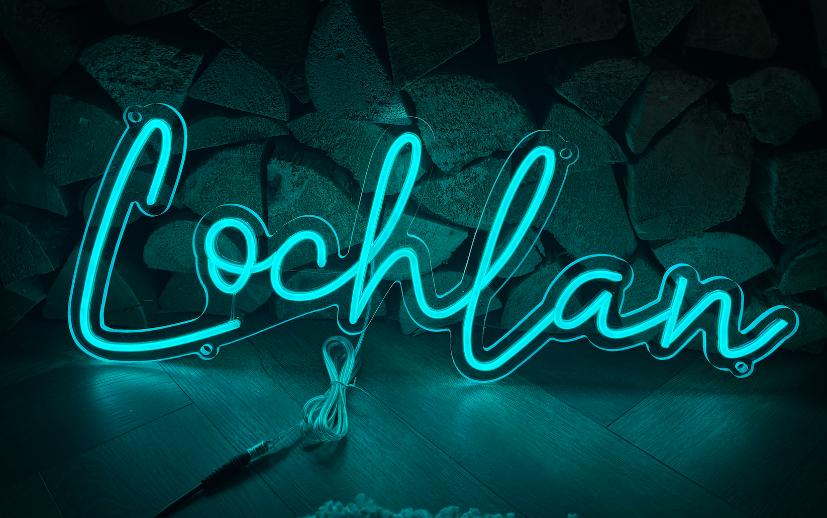a light blue neon sign in the shape of the name Lochlan