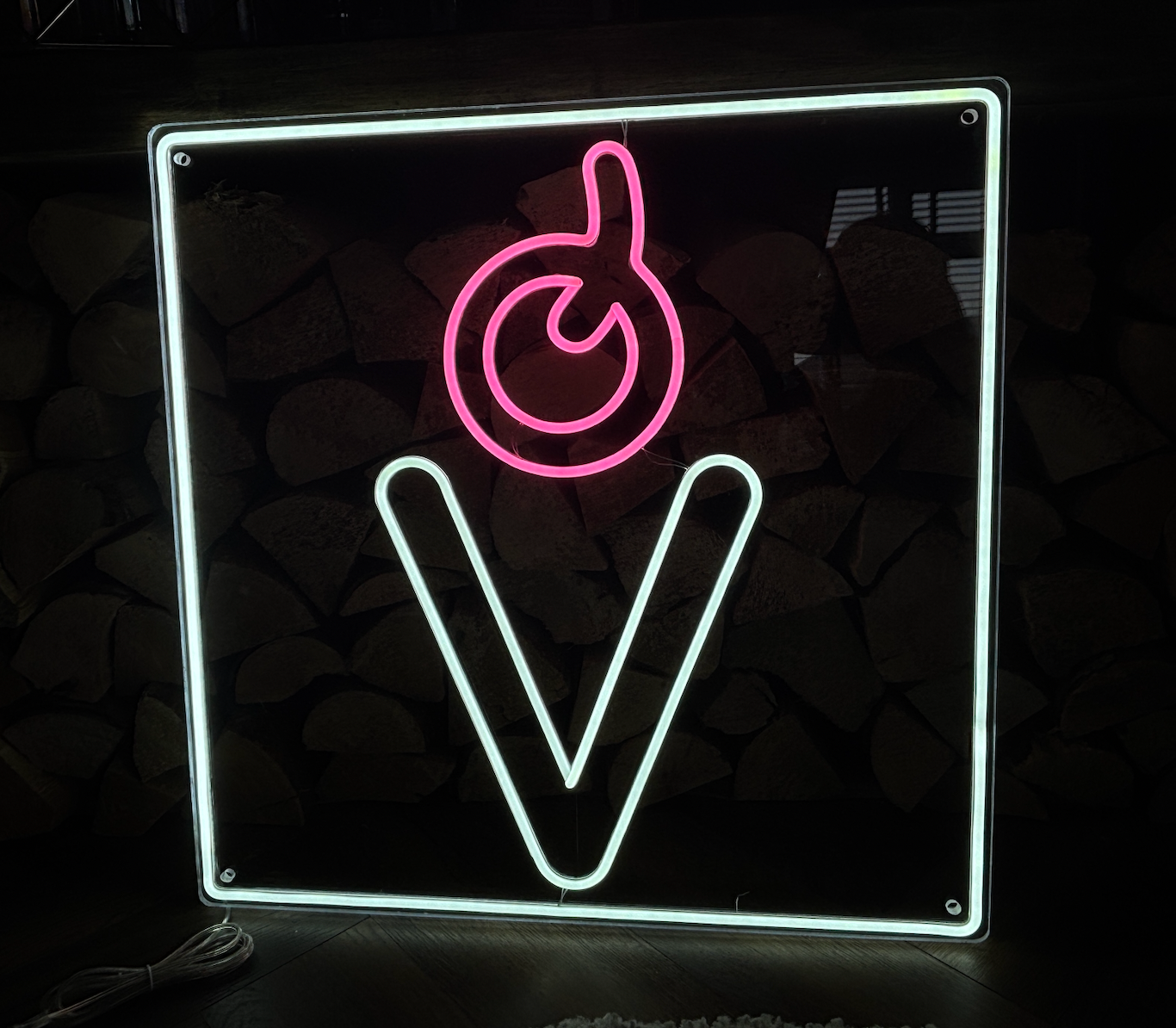 a black background, led neon sign with a white border and a light pink cherry above it