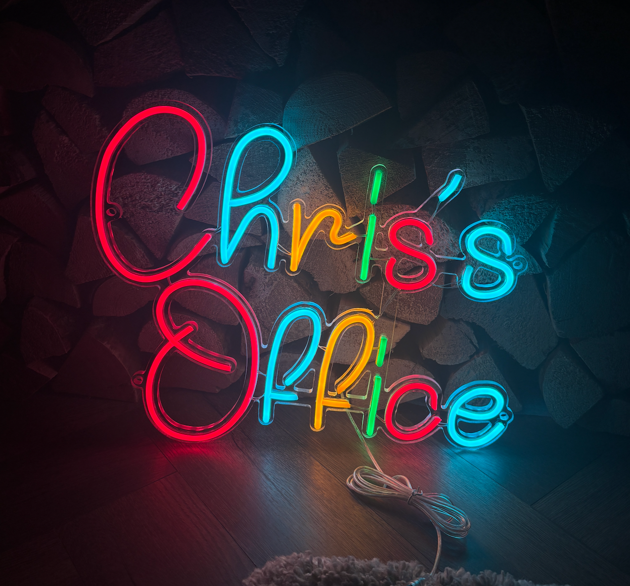 a multicoloured led neon sign using red, blue, orange and green saying chris's office