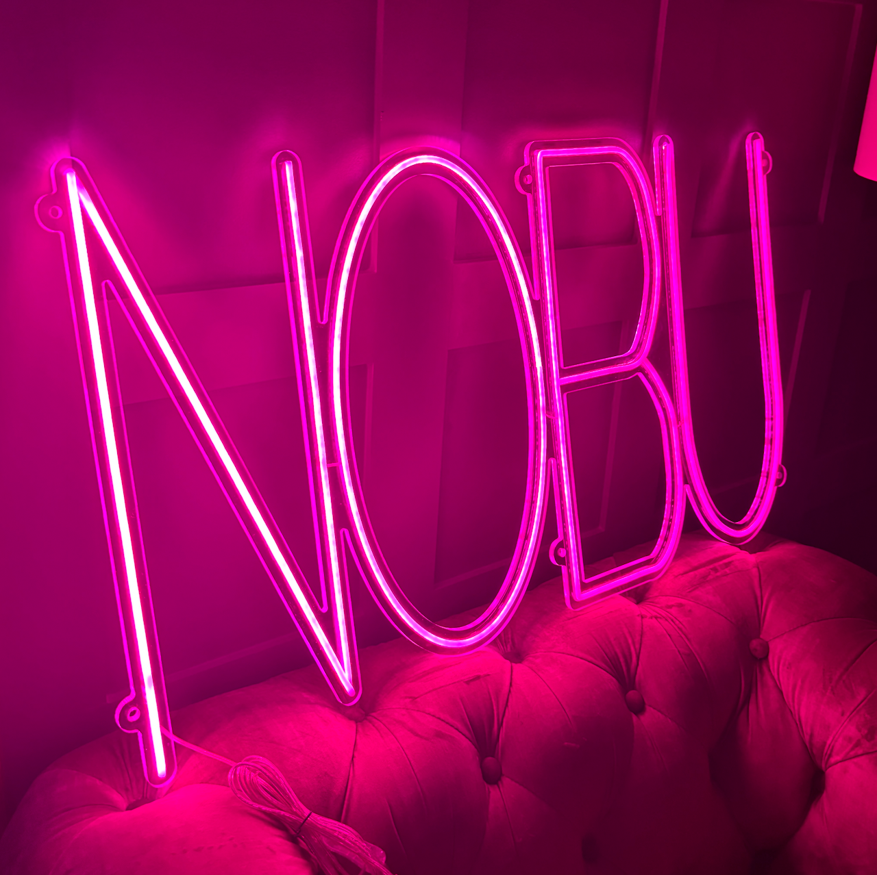 a hot pink led neon sign NOBU is the word