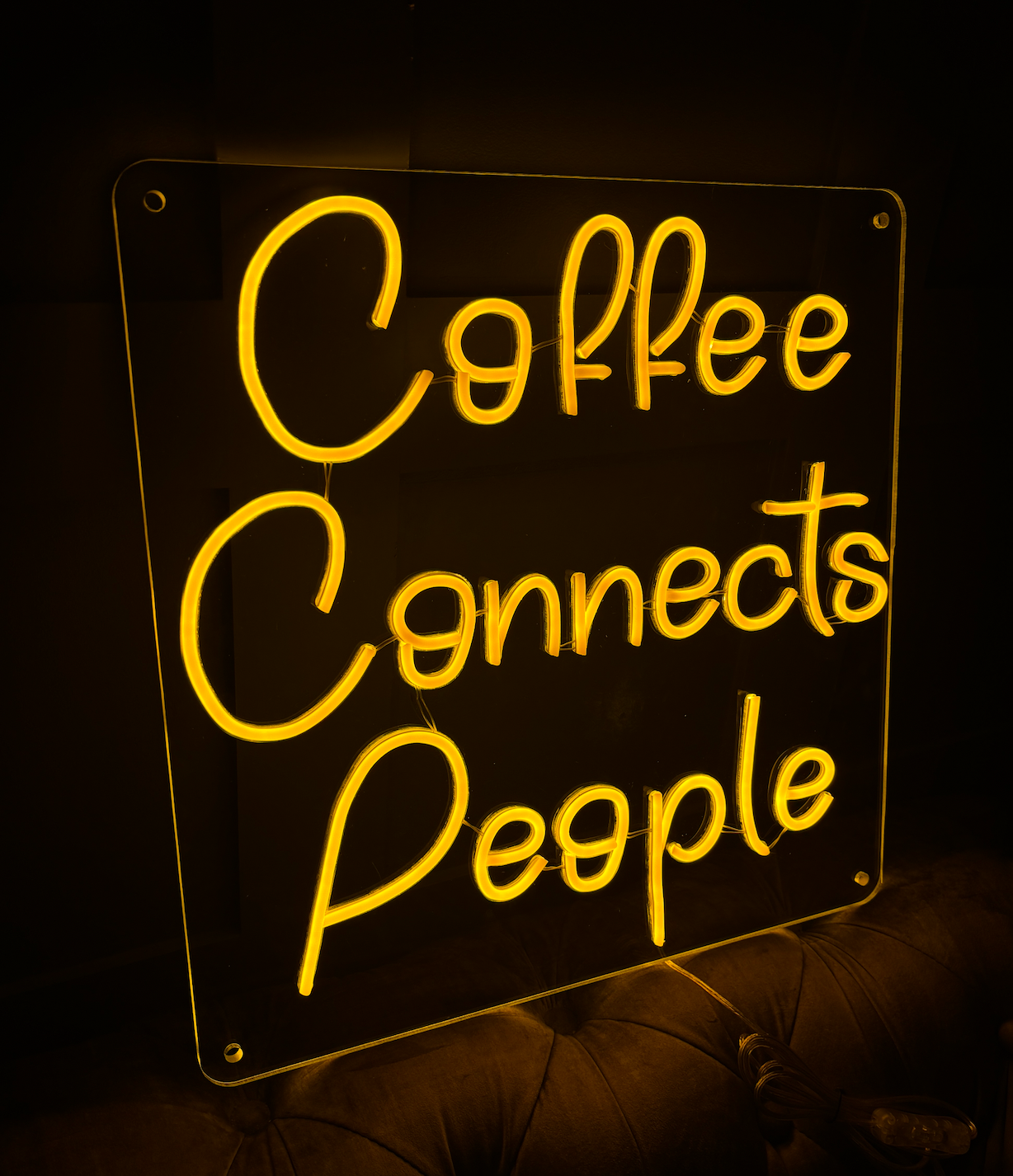 a yellow led neon sign in a square with the words coffee connects people