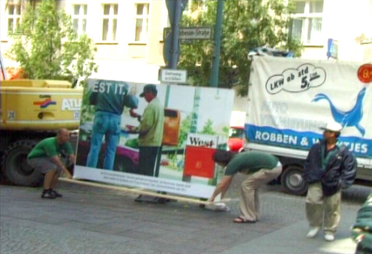 Performance/Action and later video with a pseudo advertising poster and in interaction with Vietnamese cigarette sellers. Berlin, Schönhäuser Alle, 2001. Performance/Action and later video with a pseudo advertising poster and in interaction with Vietnamese cigarette sellers. Berlin, Schönhäuser Alle, 2001.