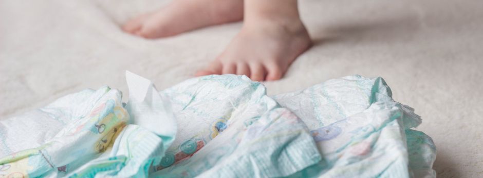 Pañales en el suelo y pies descalzos de un al lado