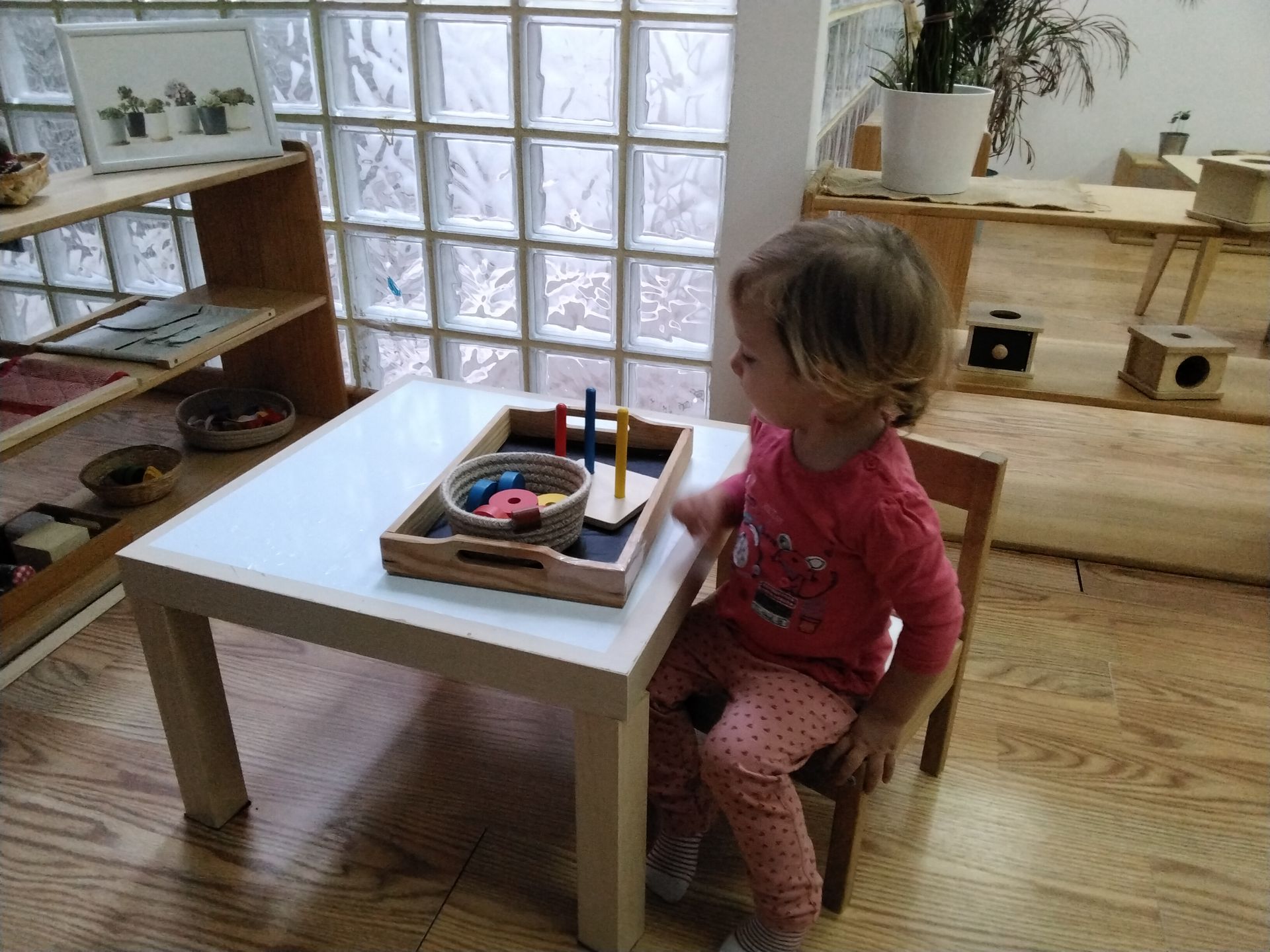 Niña sentada frente a una mesa con una bandeja que contiene una guía vertical de tres colores