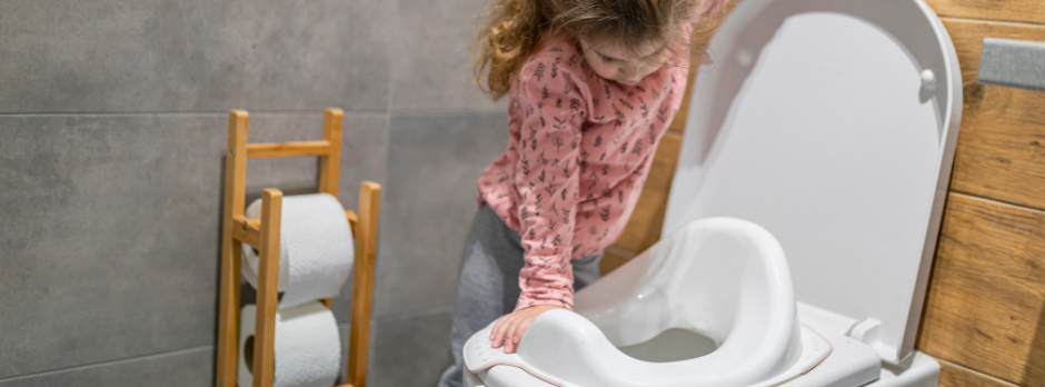 Imagen de una niña asomada a un inodoro