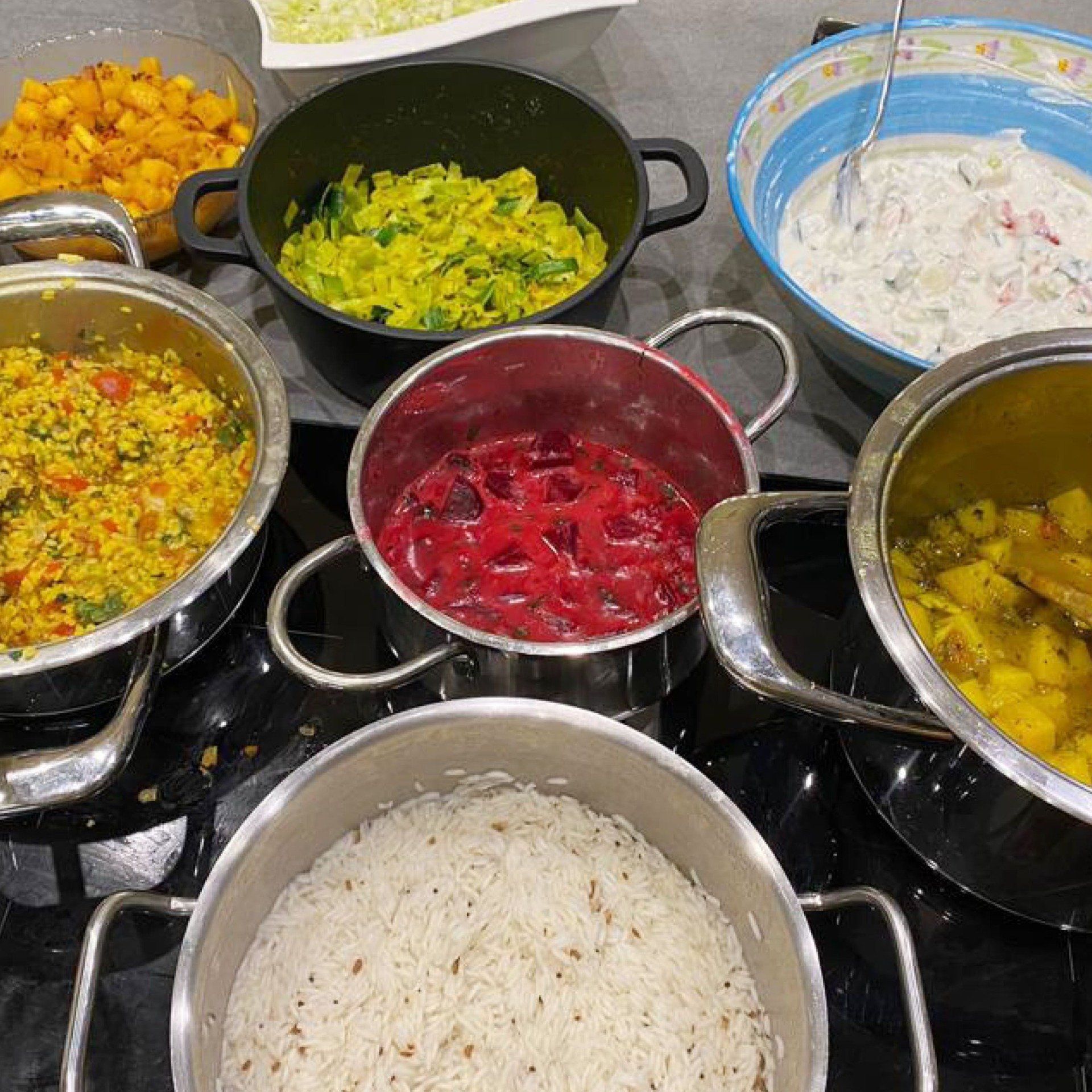 Eine Auswahl an ayurvedischen Gerichten in Kochtöpfen.