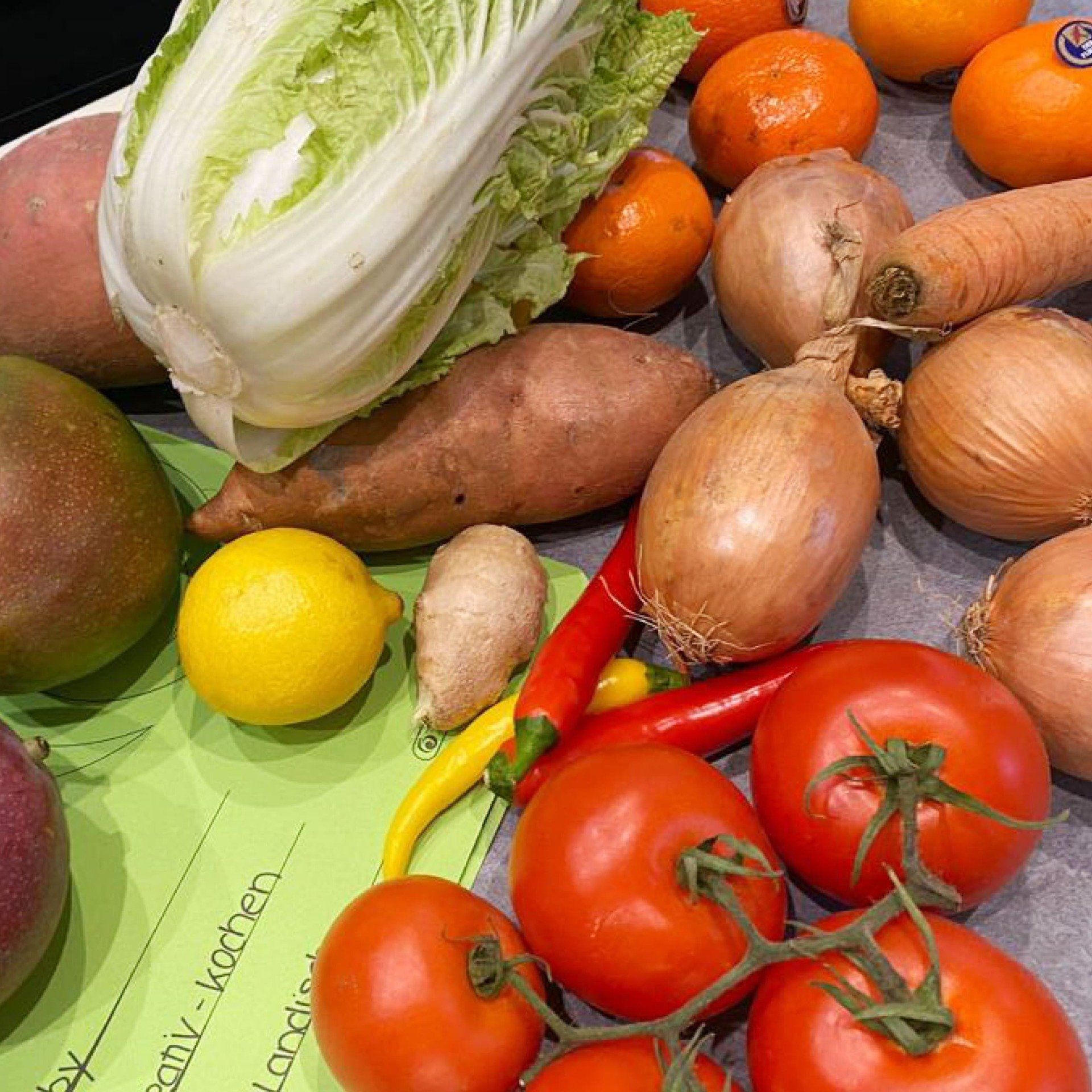Verschiedene Gemüsesorten nebeneinander: Tomaten, Zwiebeln, Chinakohl, Zitrone, Süßkartoffeln, Chili und mehr.