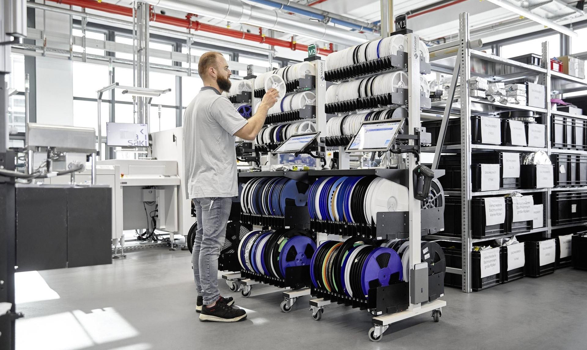 View into the Arburg materials warehouse: Man stores component reel on Inovaxe shelf