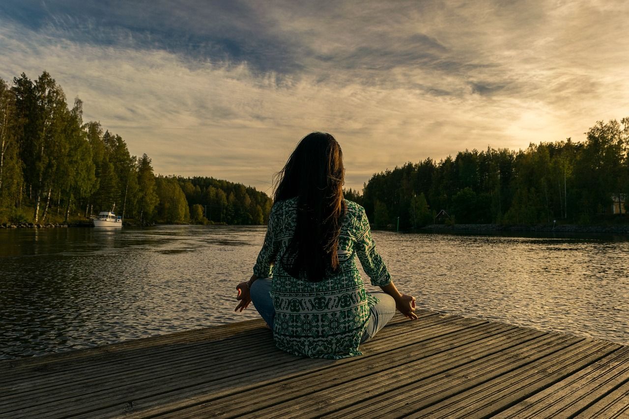 Frau sitzt am See und meditiert